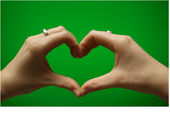 Coeur avec les mains sur fond vert Photos